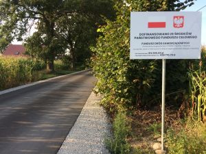 Przebudowana droga i tablica informująca o dofinansowaniu