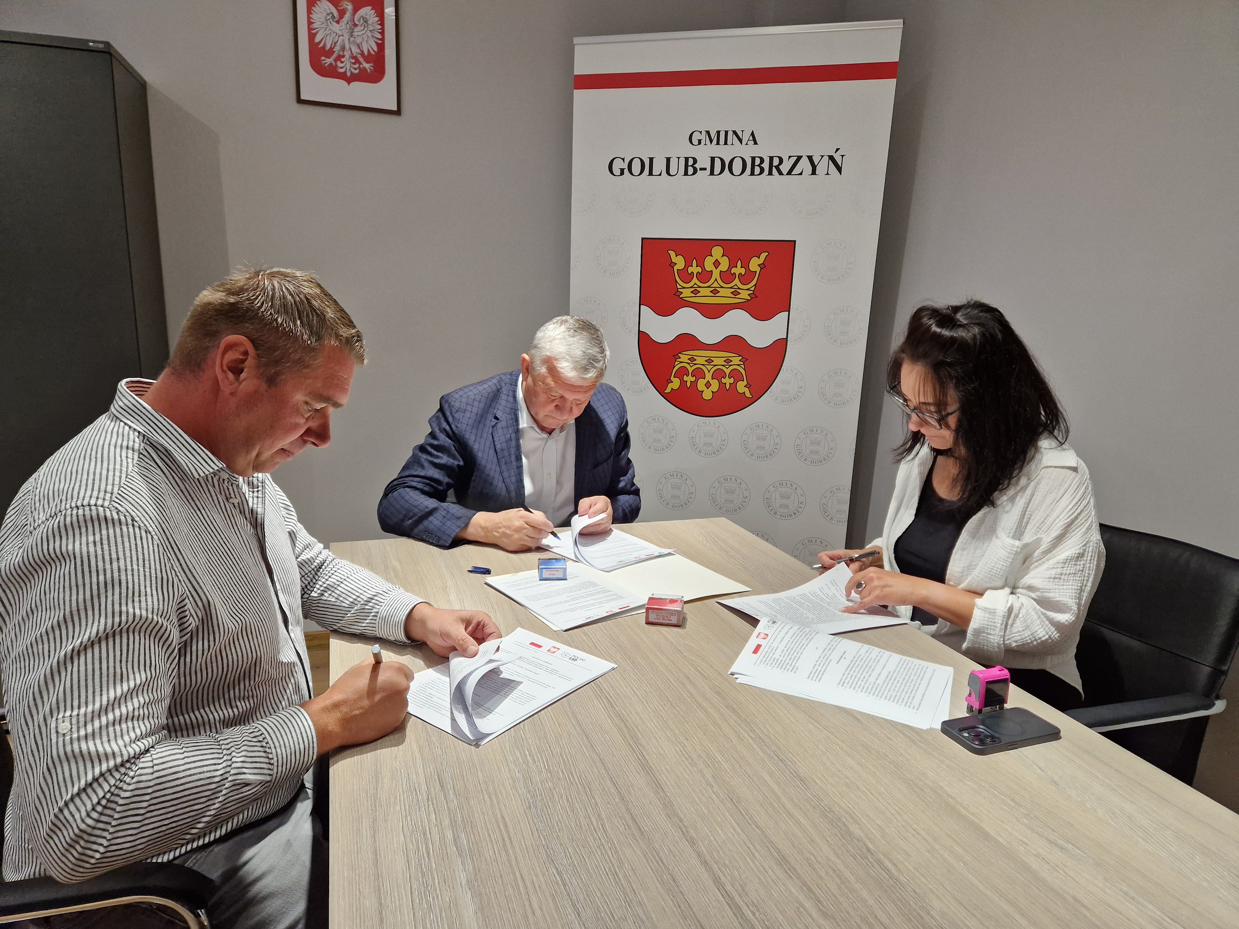 Podpisanie umowy - wójt Marek Ryłowicz, skarbnik Iwona Górska i prezes Remigiusz Zieliński